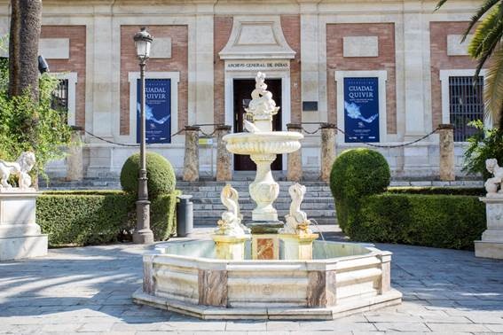 Figura 1. Fachada principal del Archivo de Indias con los carteles de la Exposición sobre el río Guadalquivir. Fuente: Surnames Comunicaciones, 2018.